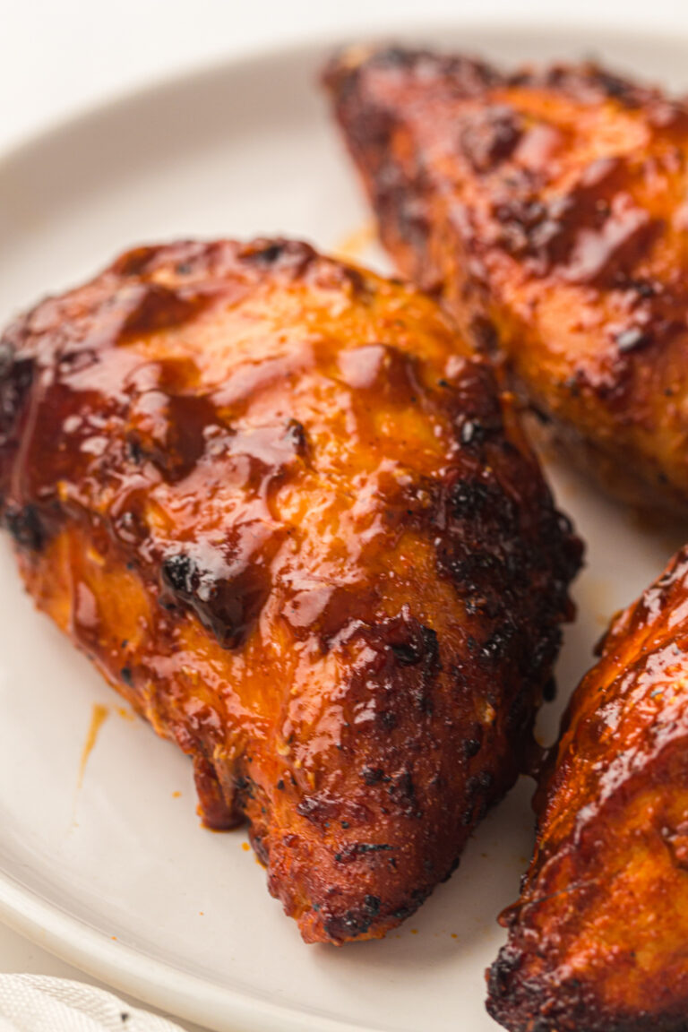 Smoked chicken breasts with a glossy barbecue glaze on a white plate.