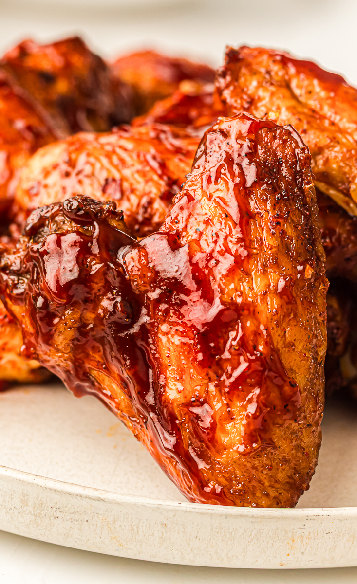 Close-up of a smoked chicken wing coated in a glossy barbecue glaze, showing caramelized skin and sticky sauce.