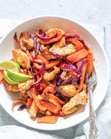 air fryer chicken fajitas served as a salad in a white bowl with fork and lime slices