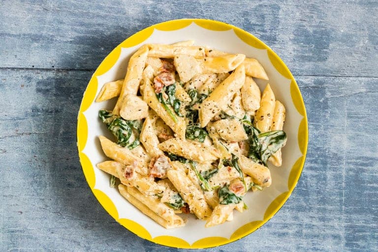 instant pot creamy tuscan chicken pasta served in a white bowl with yellow trim