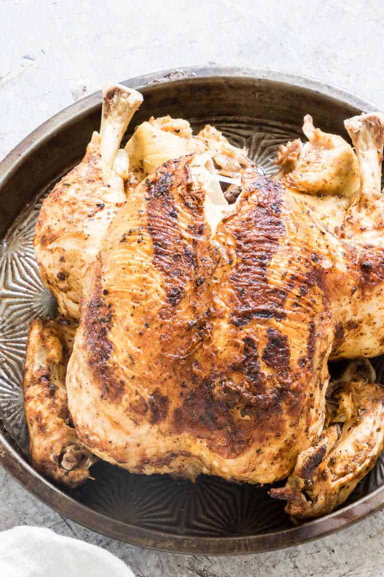closeup of browned instant pot whole chicken on a bronze platter