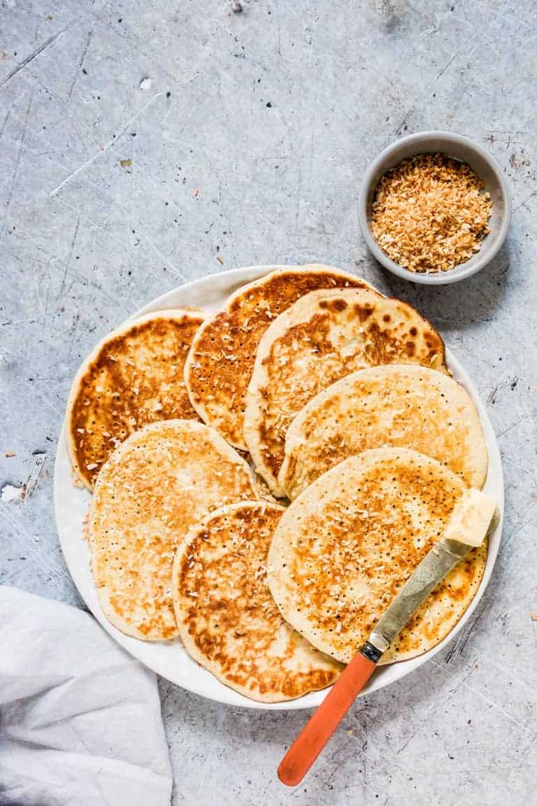 keto pancakes (low carb pancakes) on a plate with a knife, butter and a grey cloth
