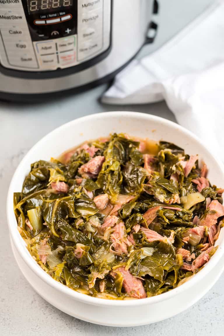 a bowl of instant pot collard greens set in front of the instant pot