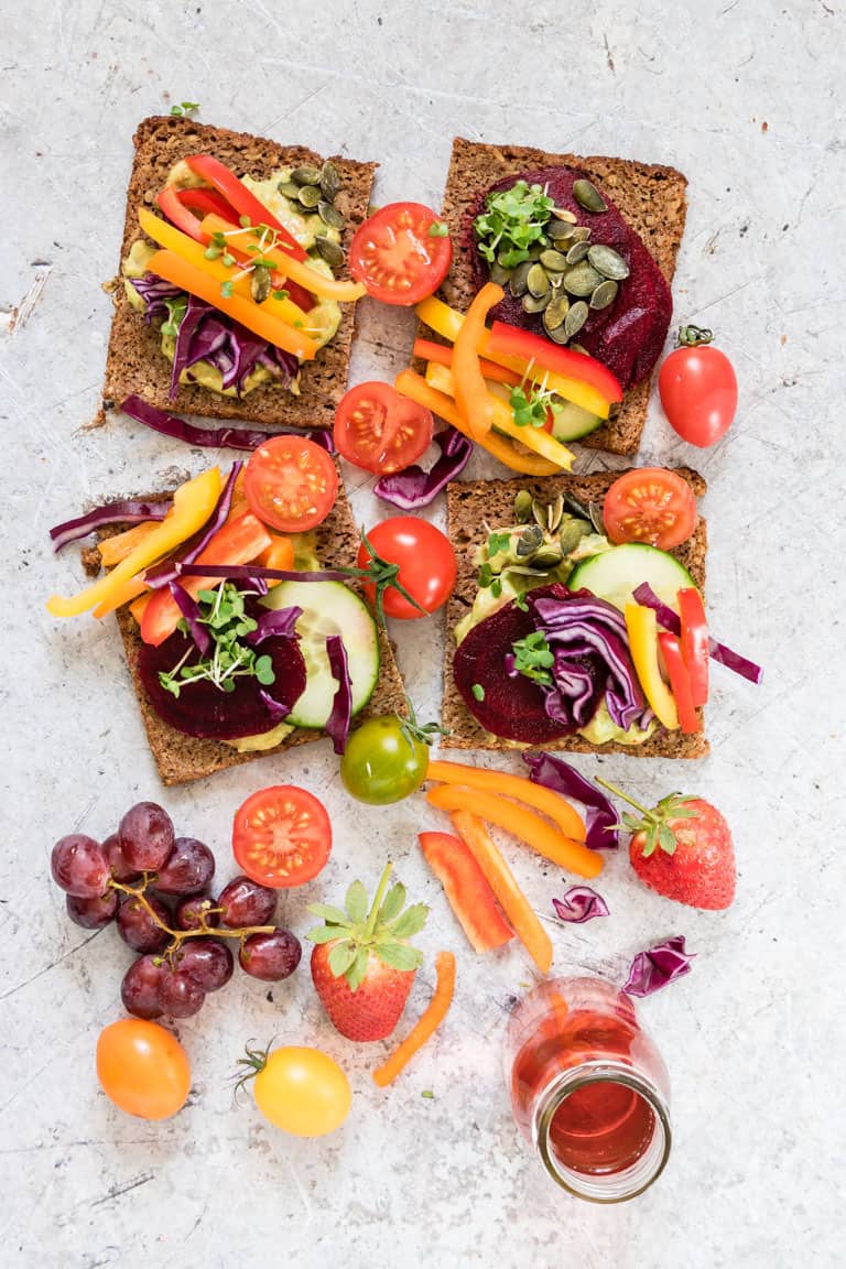 open-faced rainbow sandwich with colourful vegetables on top and around rainbow sandwiches