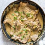 smothered pork chops in a pan and ready to serve
