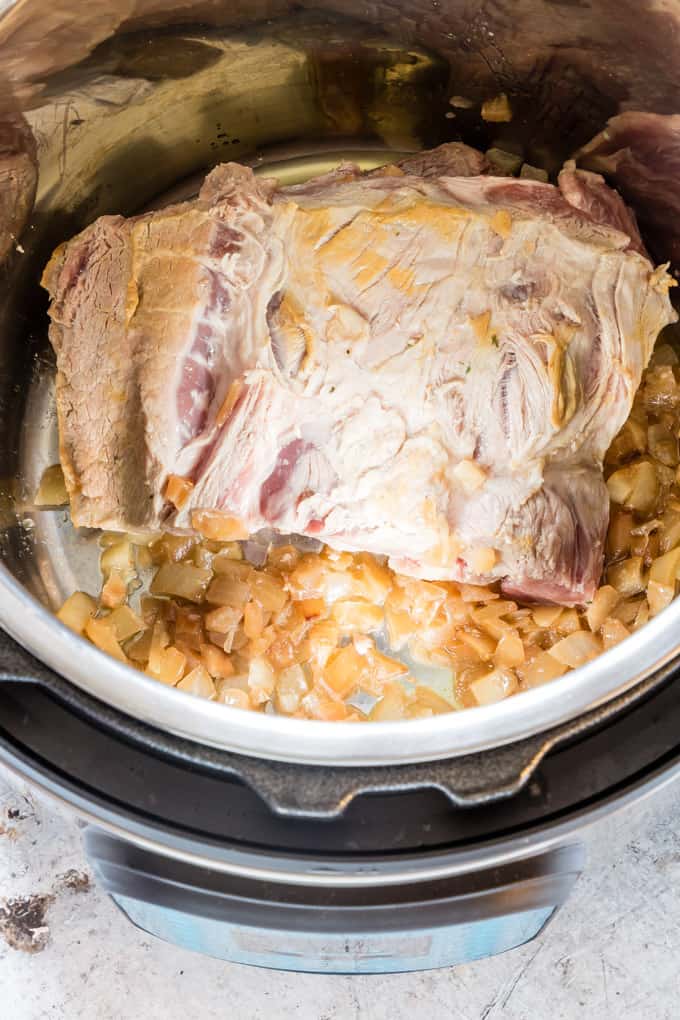 pork joint and onions for campfire stew inside of an instant pot with lid off