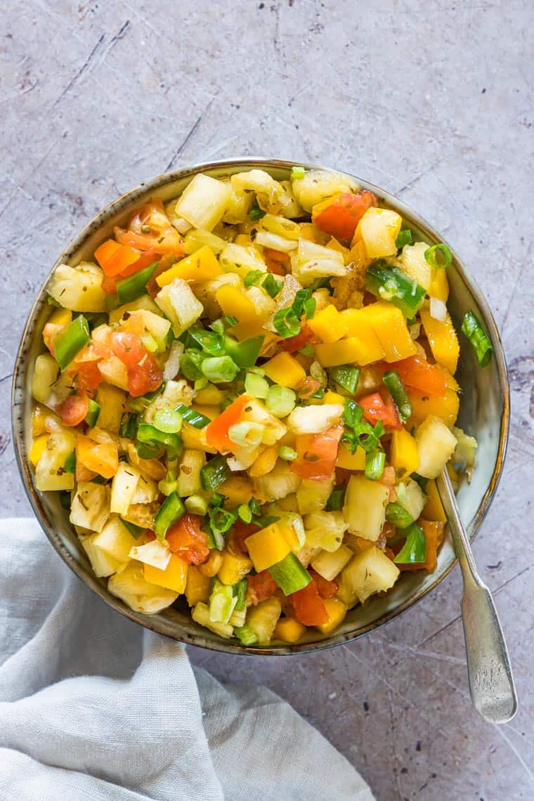 top down view of mango pineapple salsa with a serving spoon