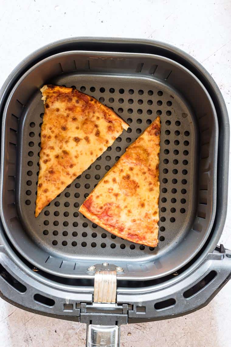 top down view of two slices of pizza in air fryer basket