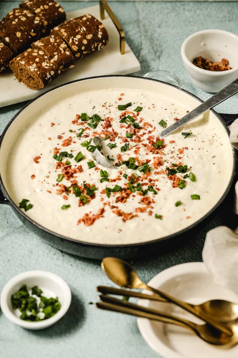 a blue bowl containing instant pot clam chowder served with bread