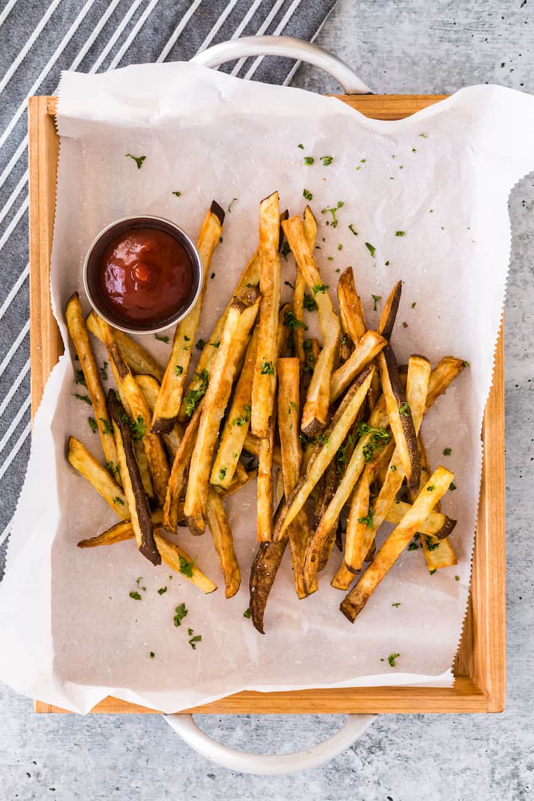 air fryer french fries on parchment paper with a side of ketchup