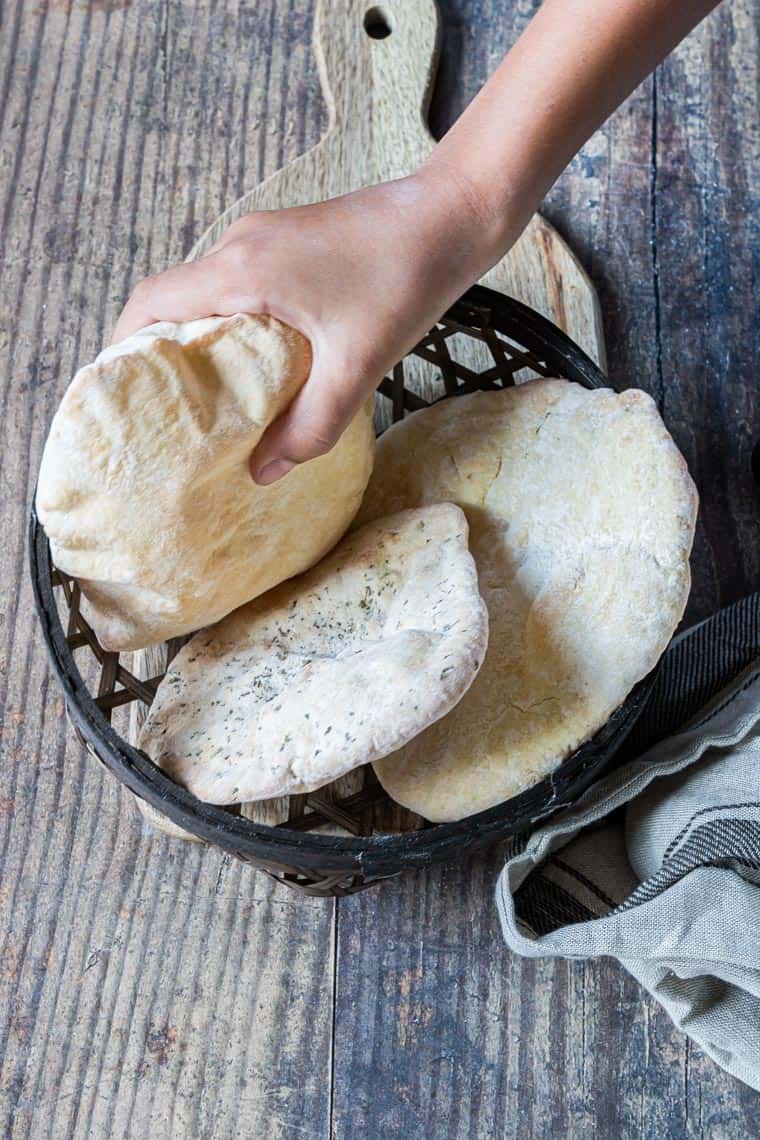 a hand removing one flatbread from a basket