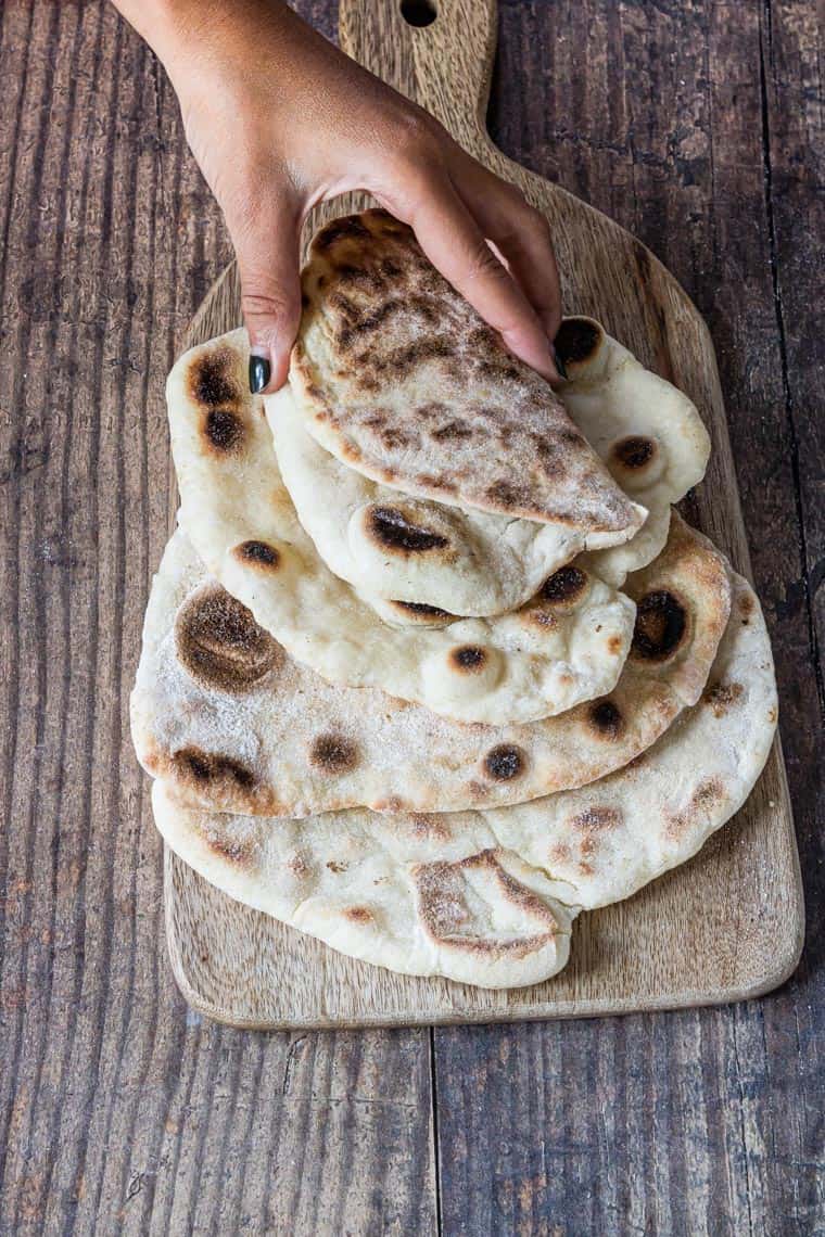 a hand reaching for a serving of the finished flatbread recipe