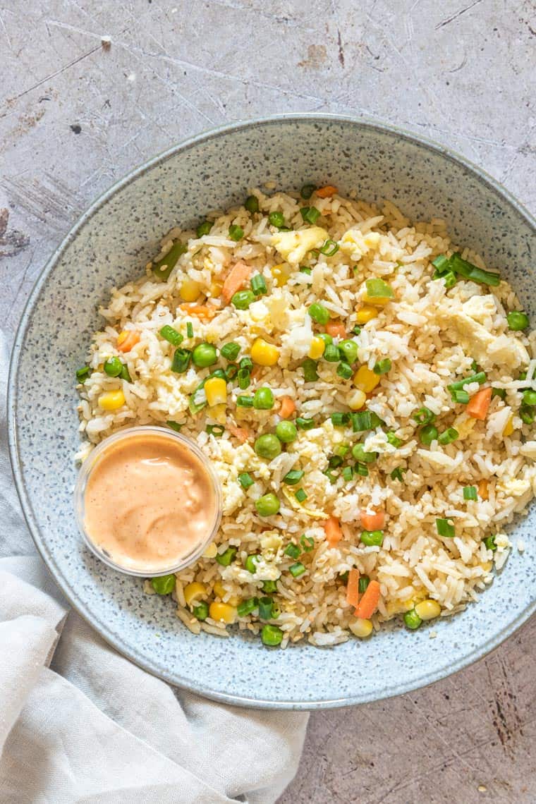 Close up of Japanese Fried Rice in a bowl with hibachi sauce in a container