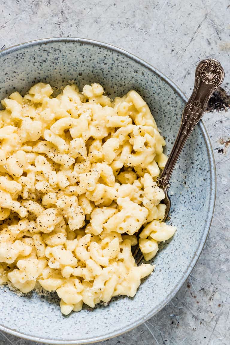 blue bowl containing instant pot mac and cheese with a spoon inside