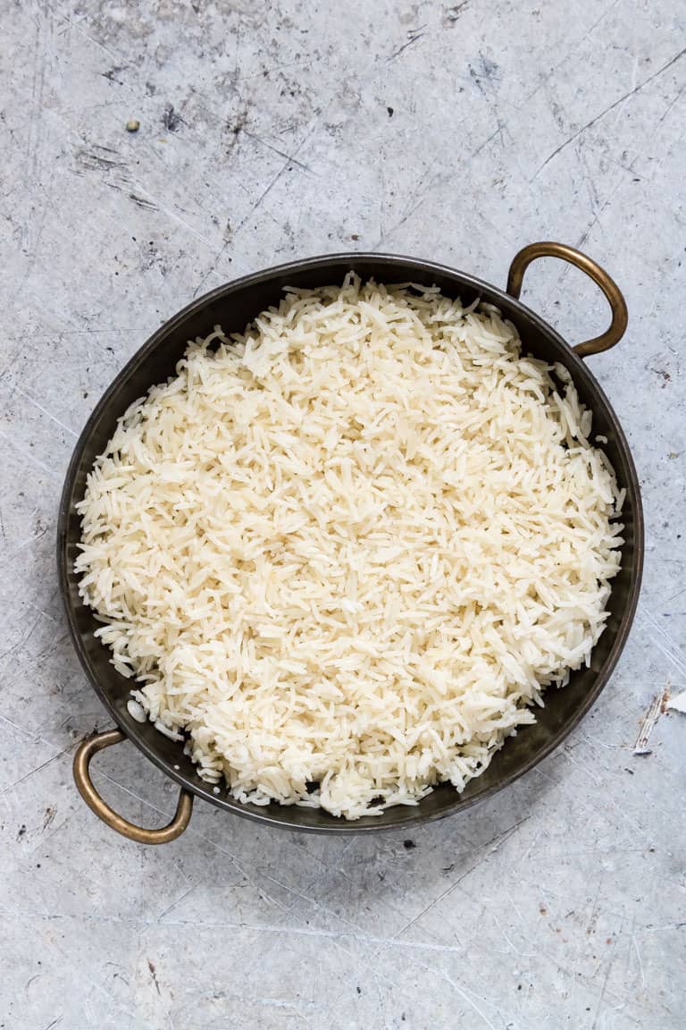 birdseye view of instant pot rice in a black bowl with handles over blue background