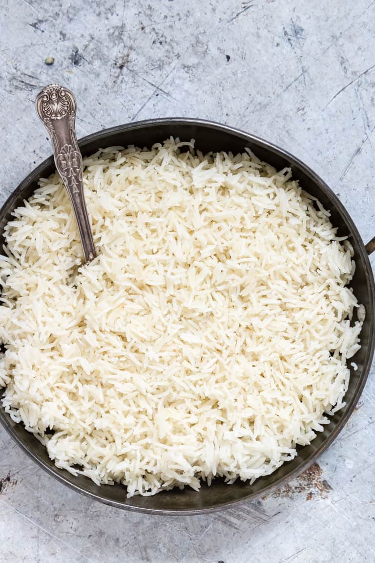 overhead view of large black bowl containing white rice with a spoon sticking out