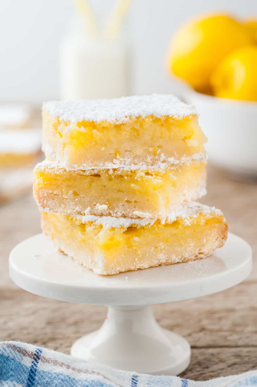 three lemon bars stacked on top of a white cake stand