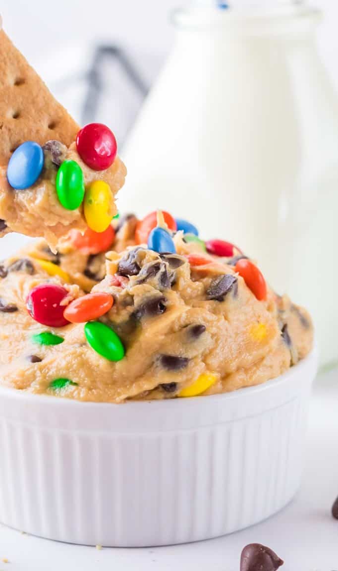 Close up of monster cookie dough dip with a graham cracker dipped in