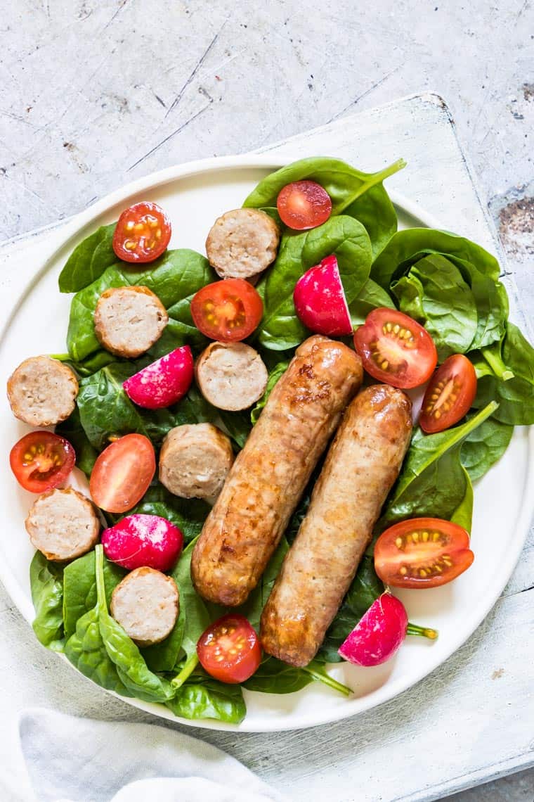 close up view of cooked air fryer sausages served on top of a green salad