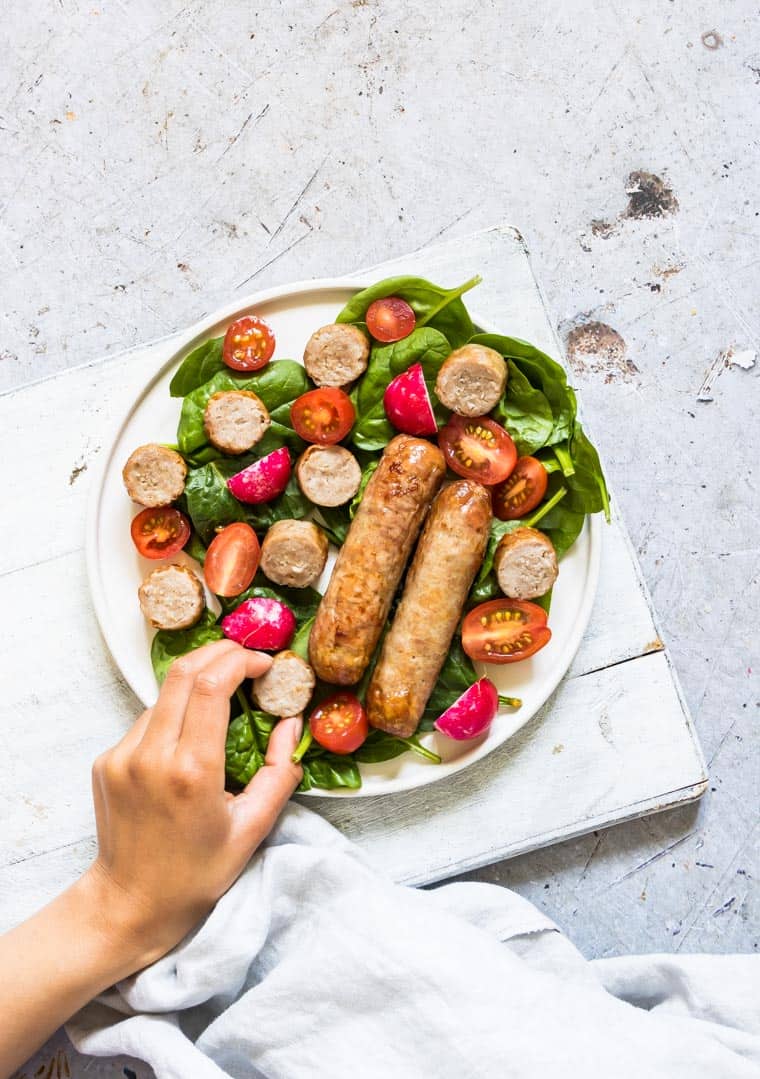 completed air fryer sausages served on top of a salad