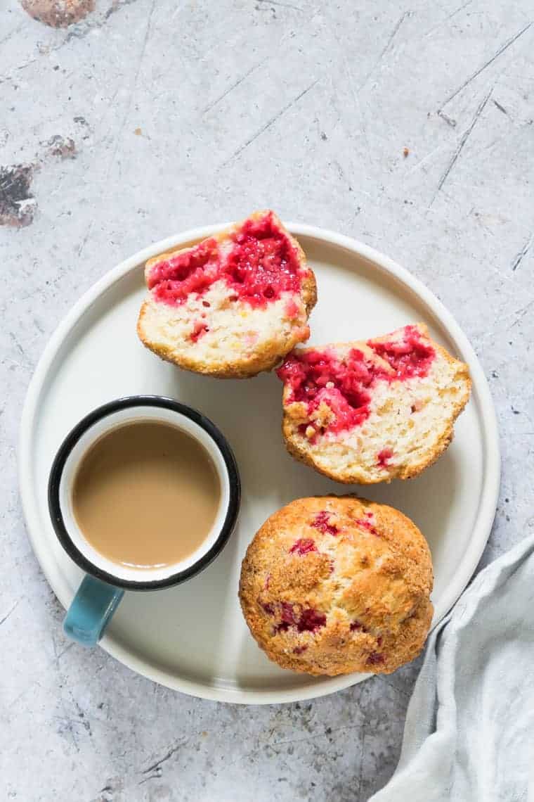 2 air fryer raspberry muffins on a plate with some tea