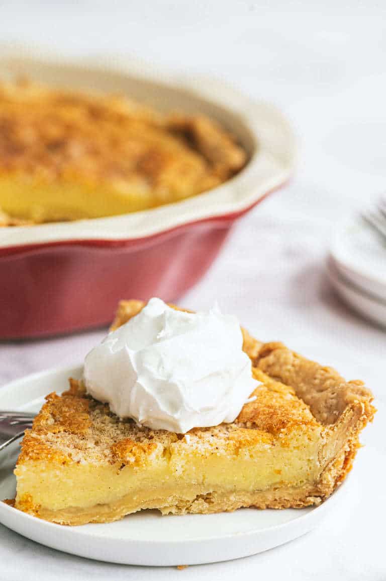 a slice of Bourbon Buttermilk Pie topped with whipped cream