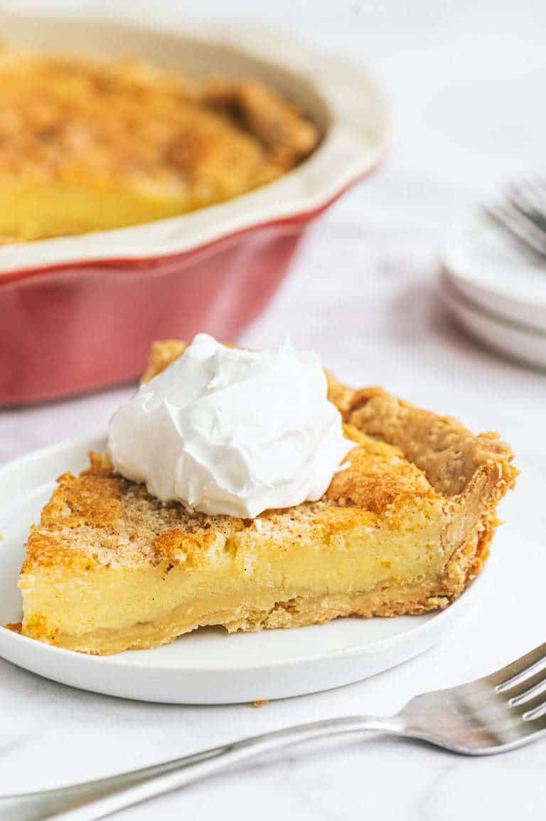 a slice of bourbon buttermilk pie removed from the pie pan and served on a white plate with a fork