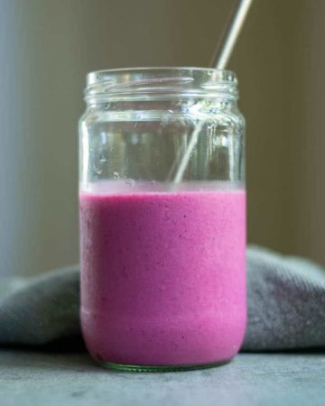 finished dragon fruit smoothie served in a glass jar with a metal straw