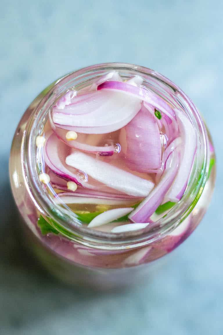 close up of the top of a jar filled with pickled onions