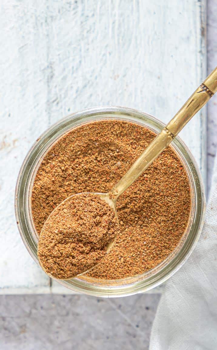 top down view of Shawarma Seasoning in a glass jar with a spoon removing one serving