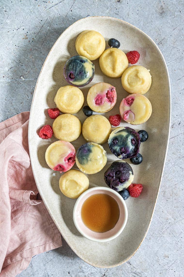 instant pot pancake bites served on a platter with a cup of syrup and fresh berries