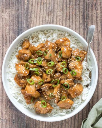 top down view of instant pot sesame chicken served over rice with a fork and green cloth napkin