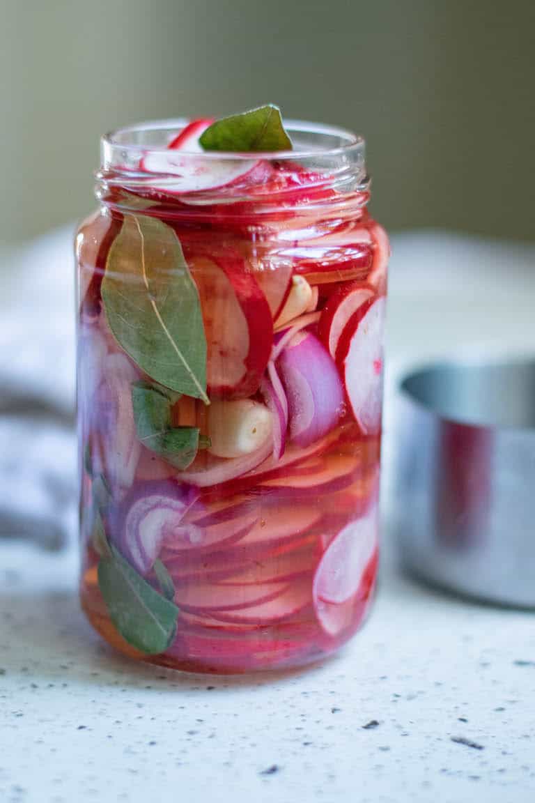a jar filled with pickled onions sitting in front of measuring cups