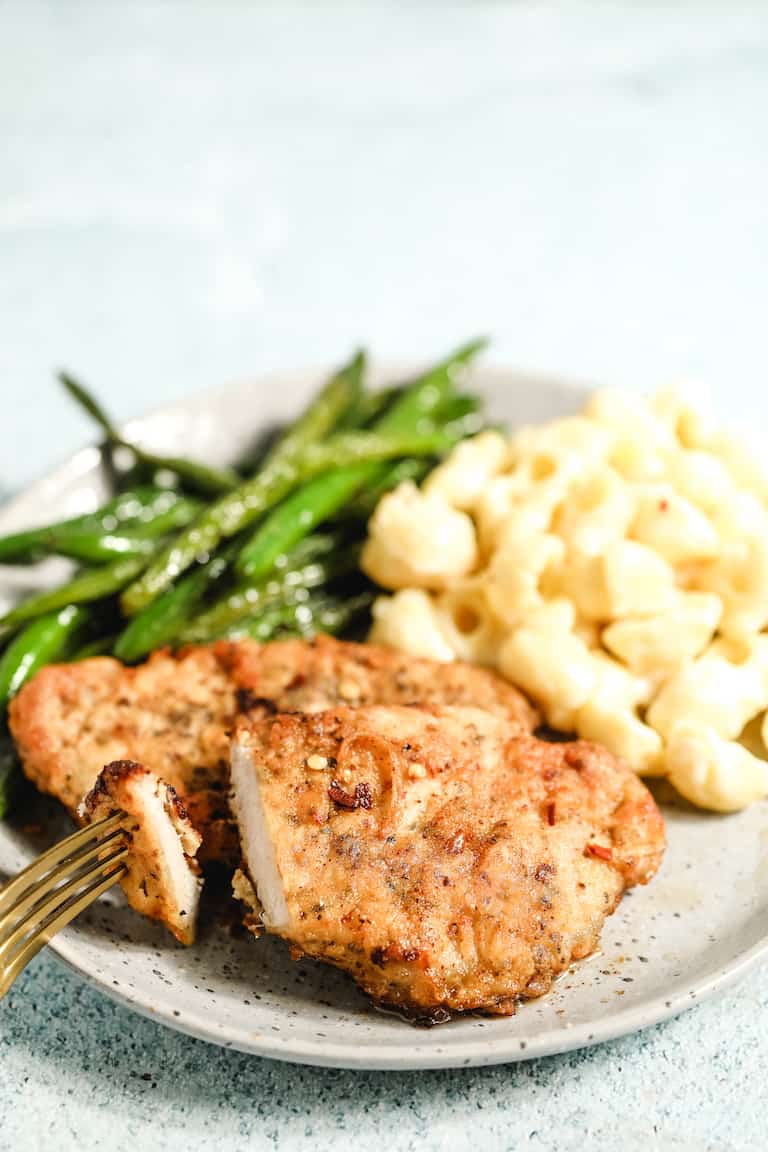 southern fried pork chops and gravy served on a white plate with green beans and mac and cheese