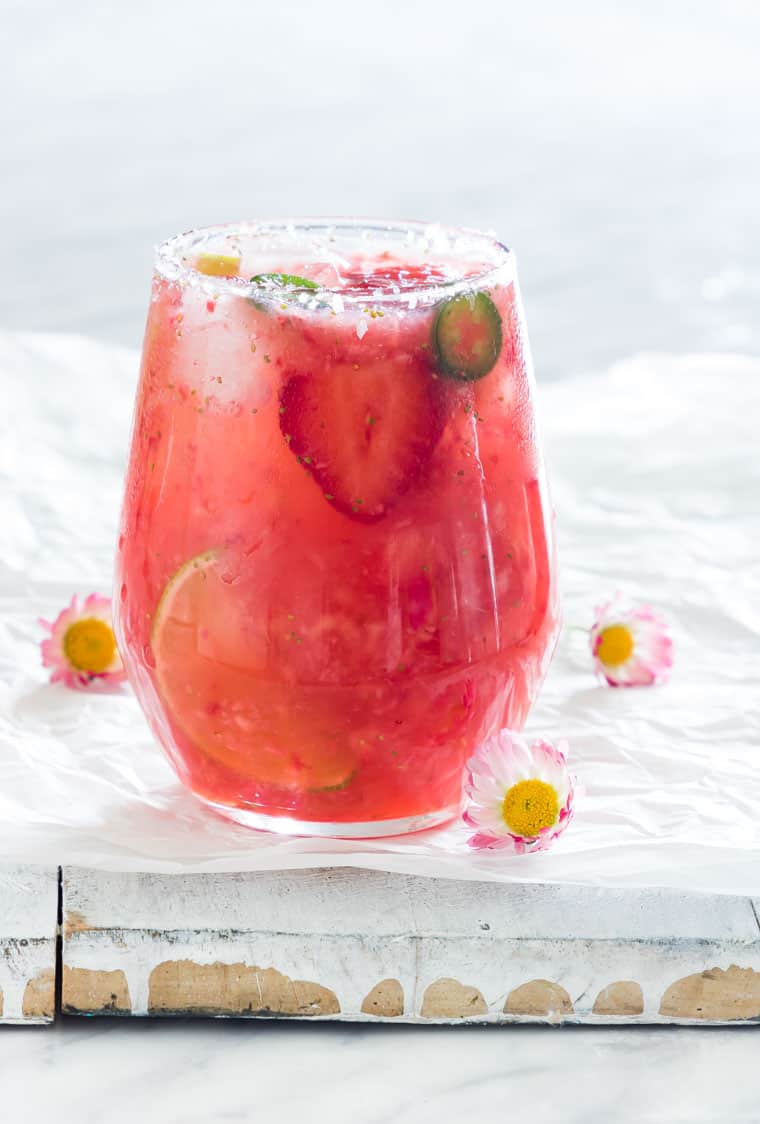 A glass of strawberry margarita with garnishes