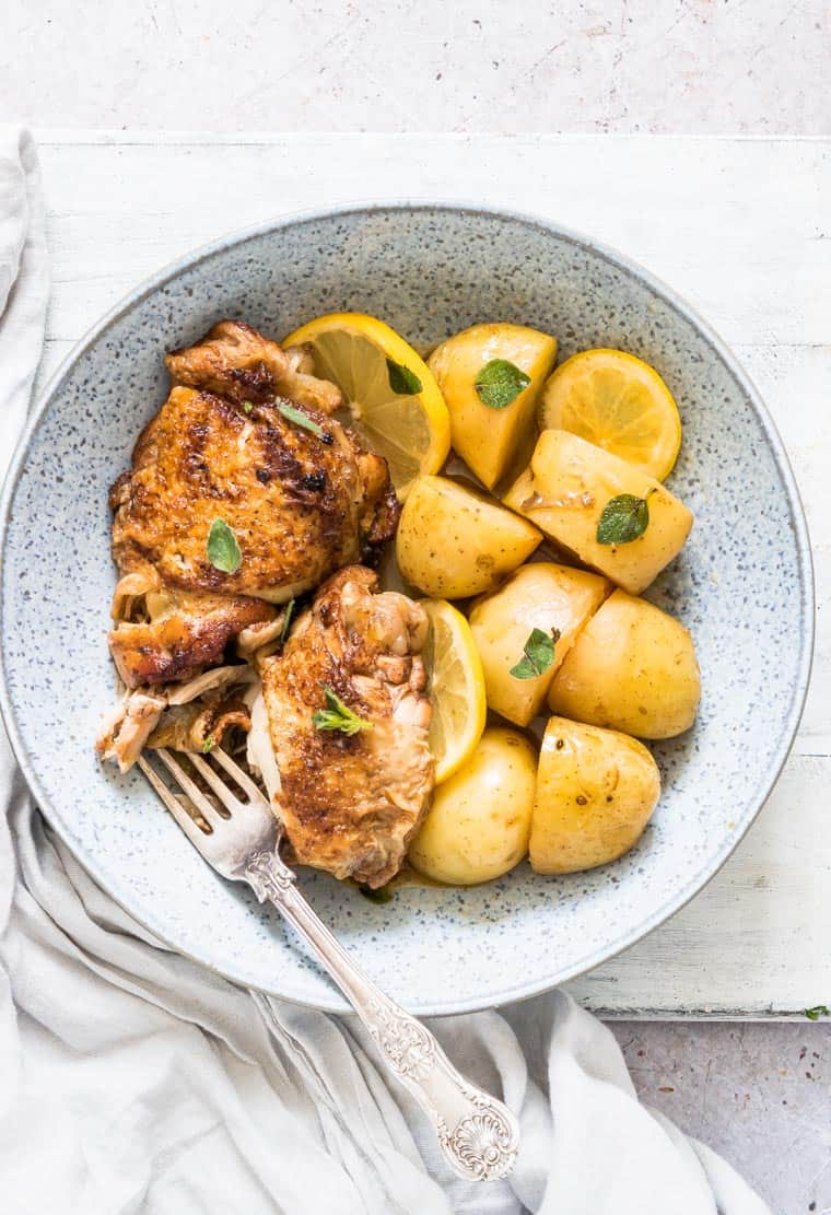 Instant Pot Chicken and Potatoes served in a blue bowl with fork and cloth napkin