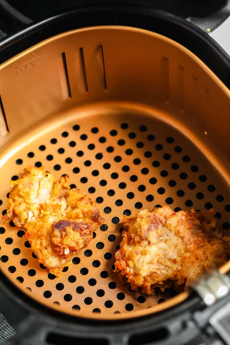 two pieces of air fryer fried chicken inside the air fryer basket