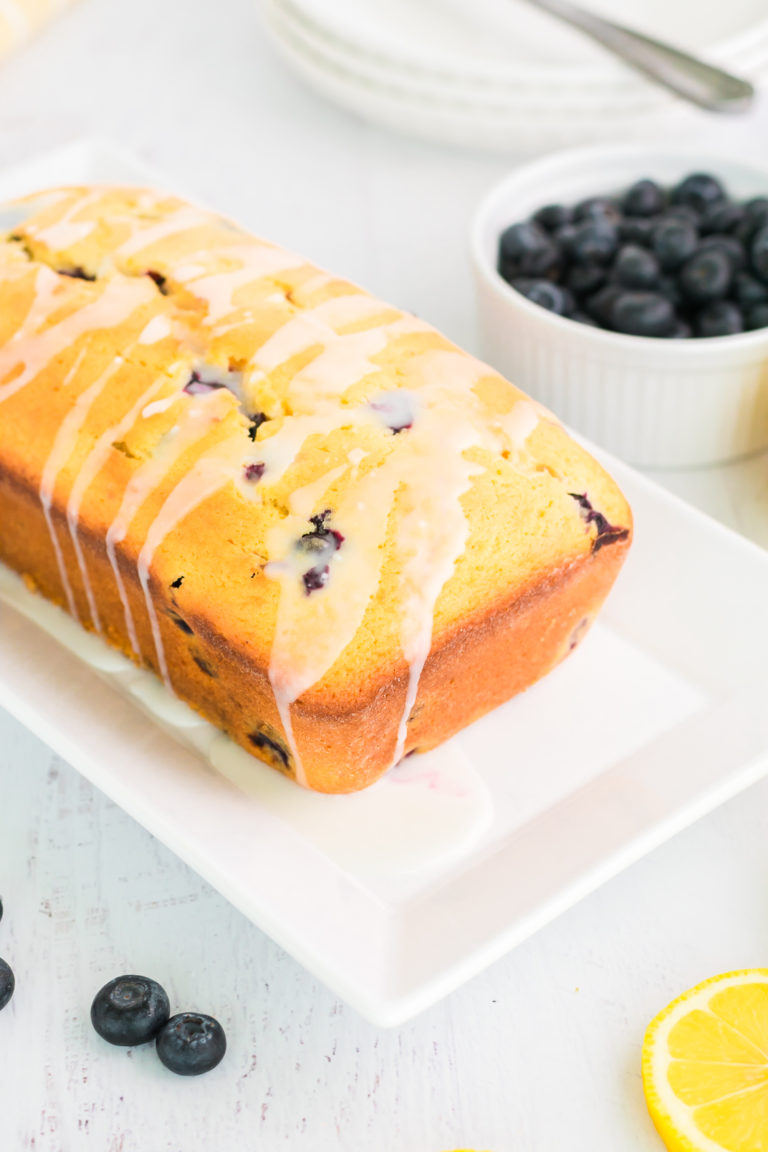 blueberry lemon bread topped with lemon glaze and served on a white plate