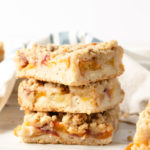 three peach crumb bars stacked on top of each other