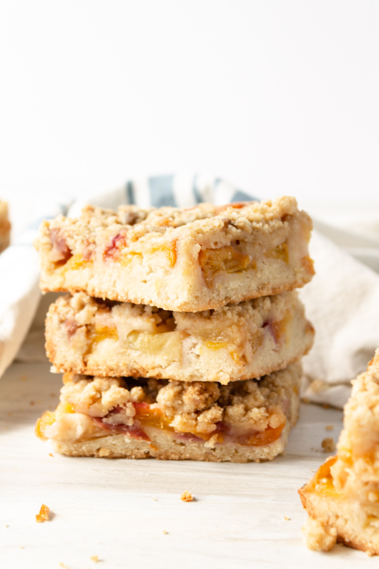 three peach crumb bars stacked on top of each other