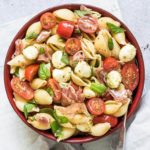 caprese pasta salad with parma ham served in a red bowl