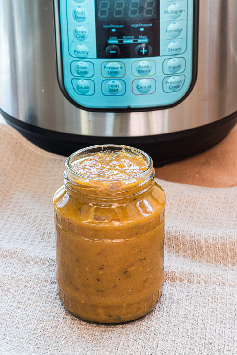 a jar of the finished mango chutney in front of the instant pot