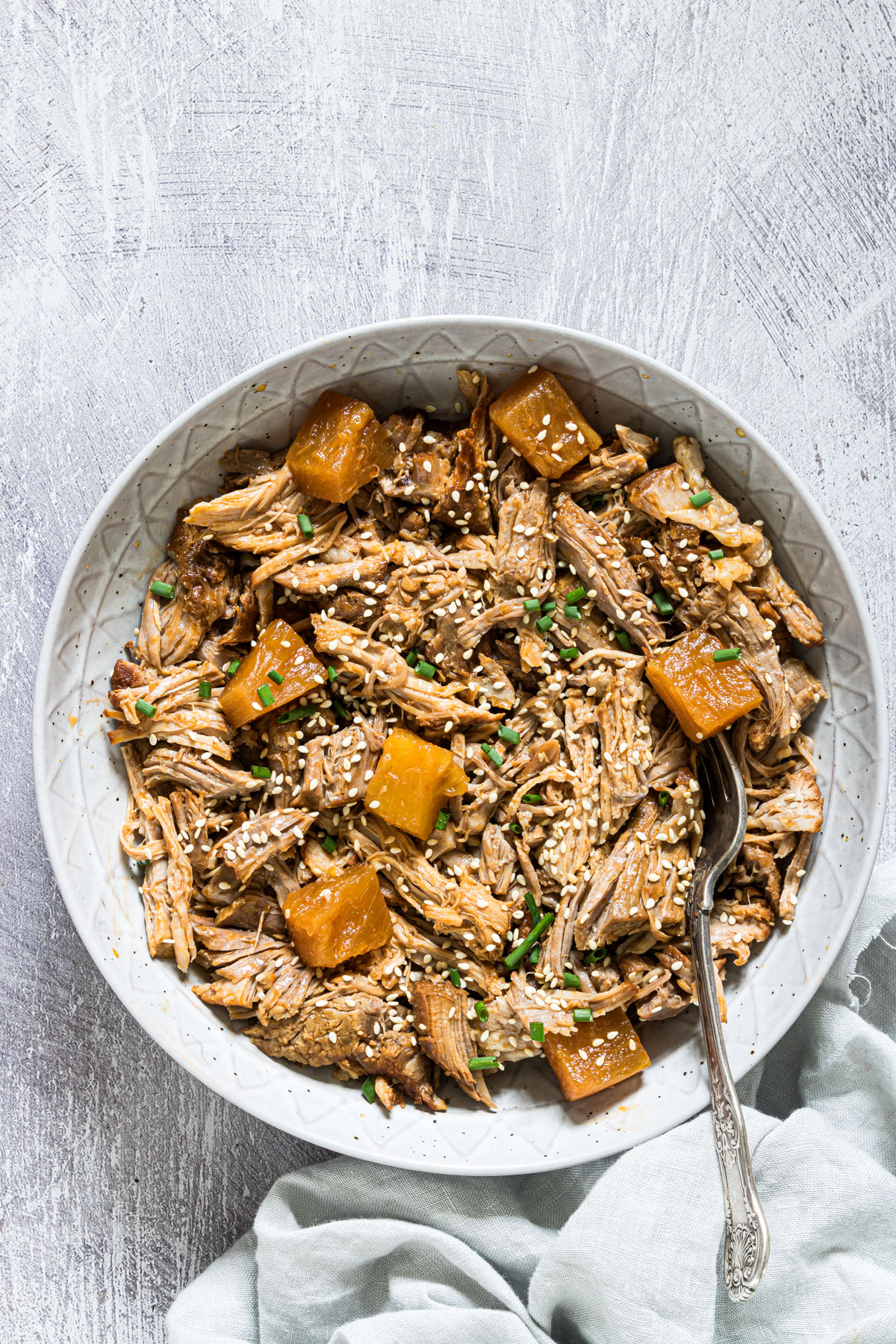 a plate of the completed instant pot pulled pork with a fork and cloth napkin