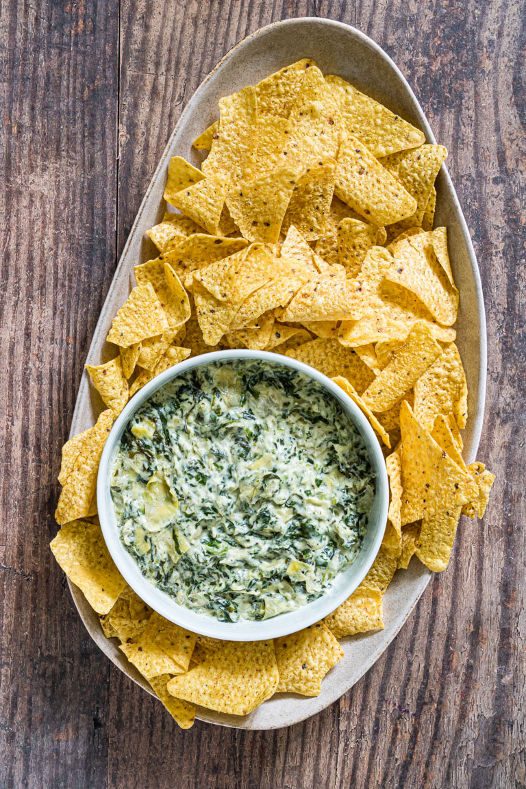 instant pot spinach artichoke dip in a white bowl on a platter with tortilla chips