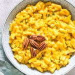 a bowl filled with instant pot pumpkin mac and cheese ands garnished with toasted pecans