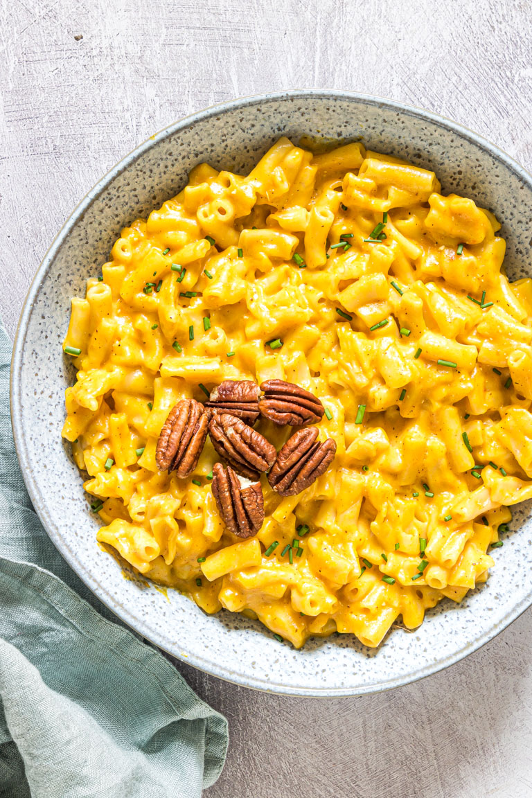 a bowl filled with instant pot pumpkin mac and cheese ands garnished with toasted pecans