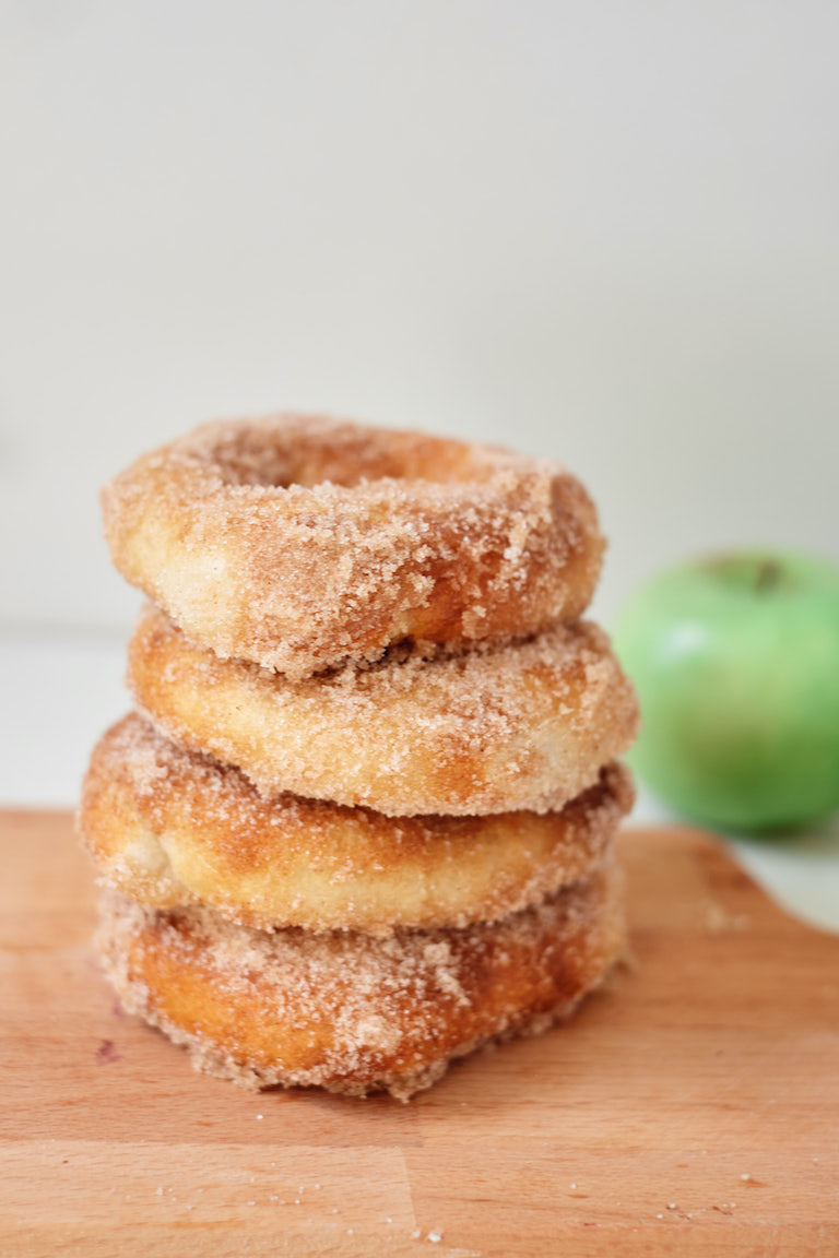 a stack of four air fryer caramel apple donuts on a cutting board