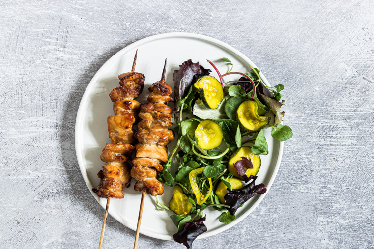 finished air fryer chicken kabobs served with a salad on a white plate
