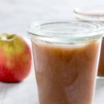 A jar full of Instant Pot Applesauce with apple and another jar in the background