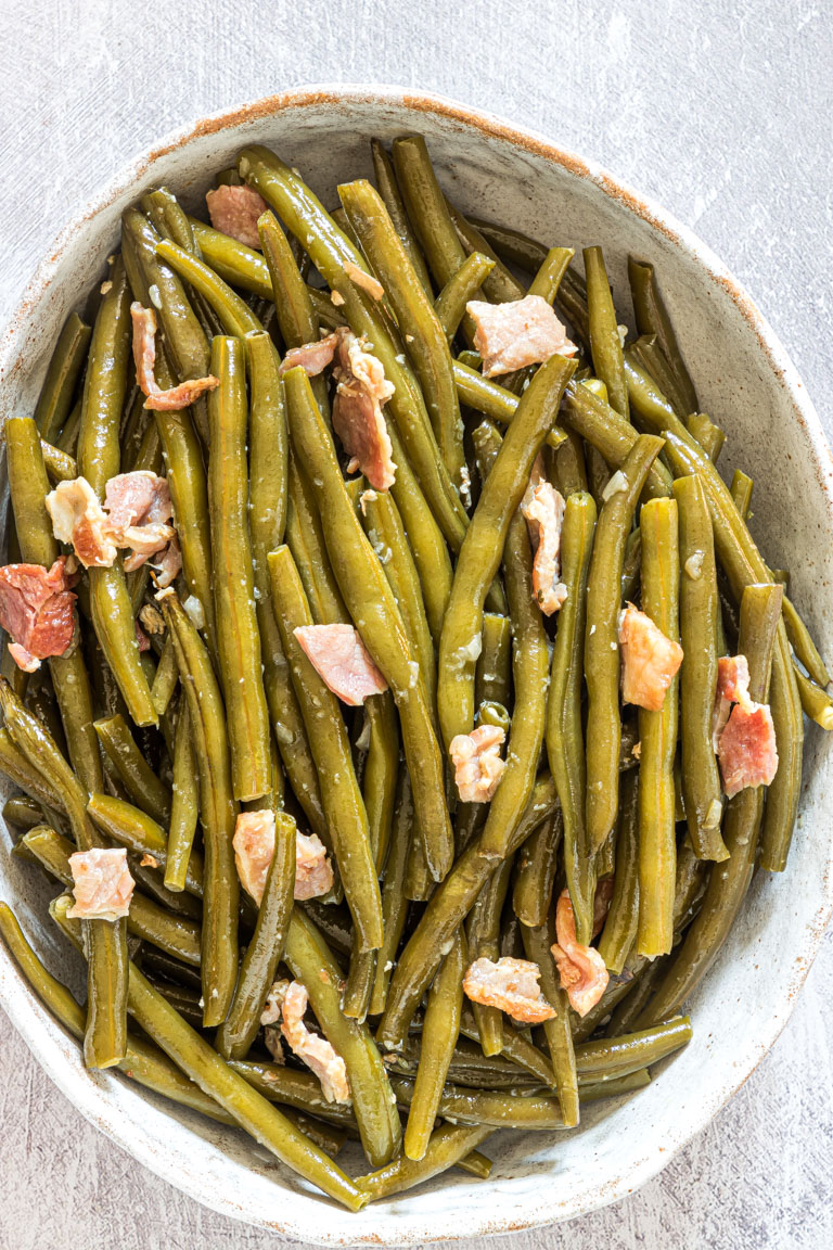 crockpot green beans with bacon bit in a clay serving plate.